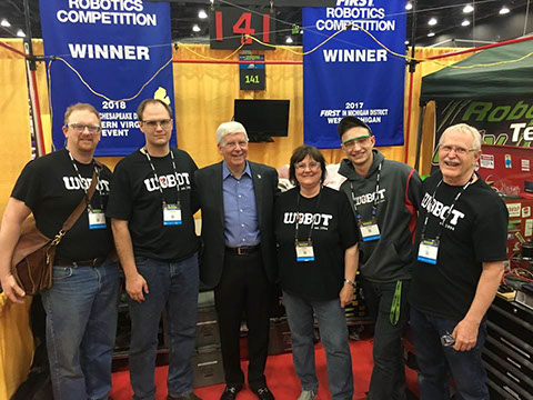 Four of our mentors and one student posing with Michigan's Governor Rick Snyder in our pit.