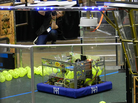 Our robot getting in position to shoot, with our team photographer Livia ready to capture it.